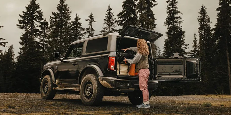 A person loading camping gear in to the back of a 2025 For Bronco.